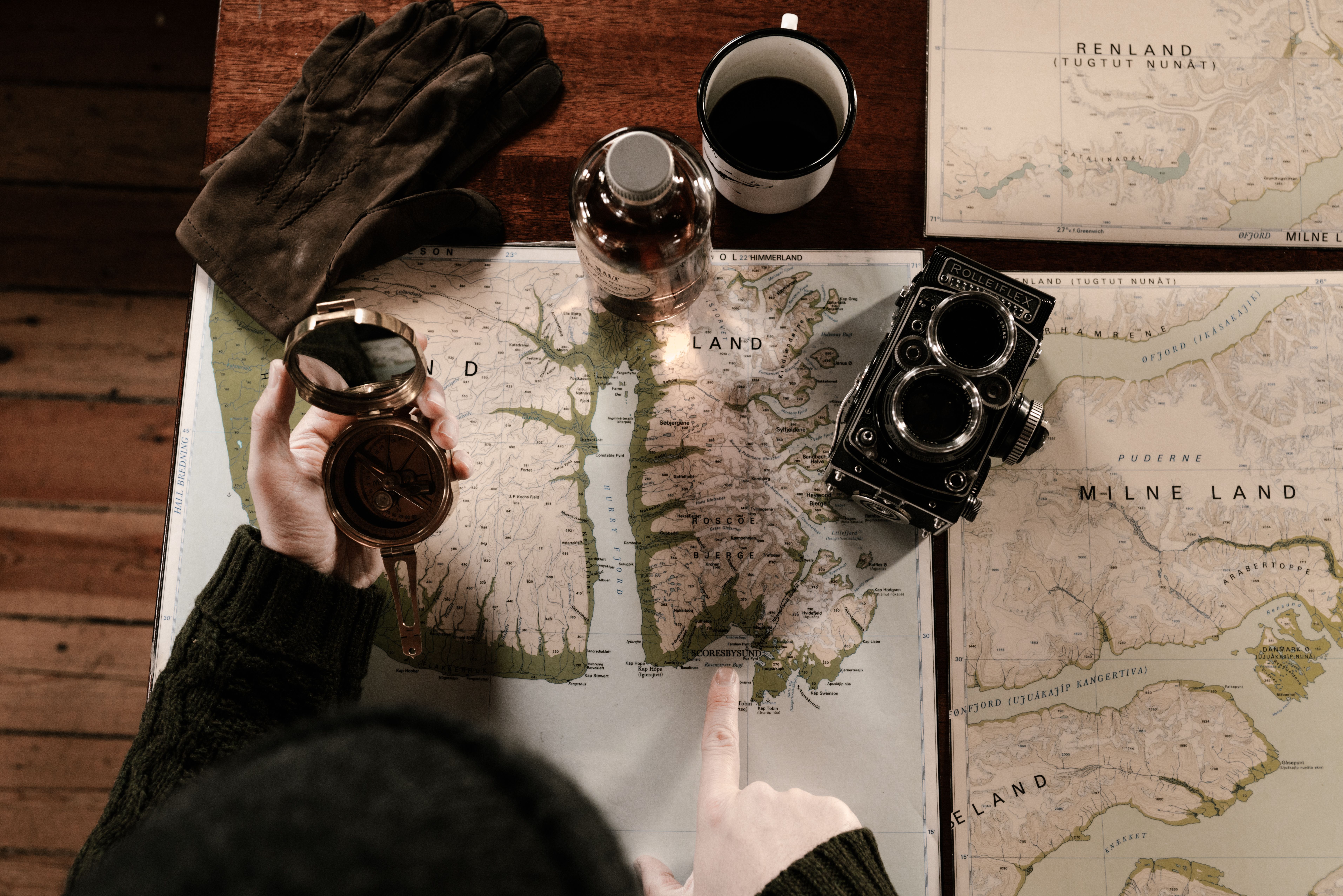 Top view of a vintage travel setup with maps, compass, gloves and camera for verifying itinerary