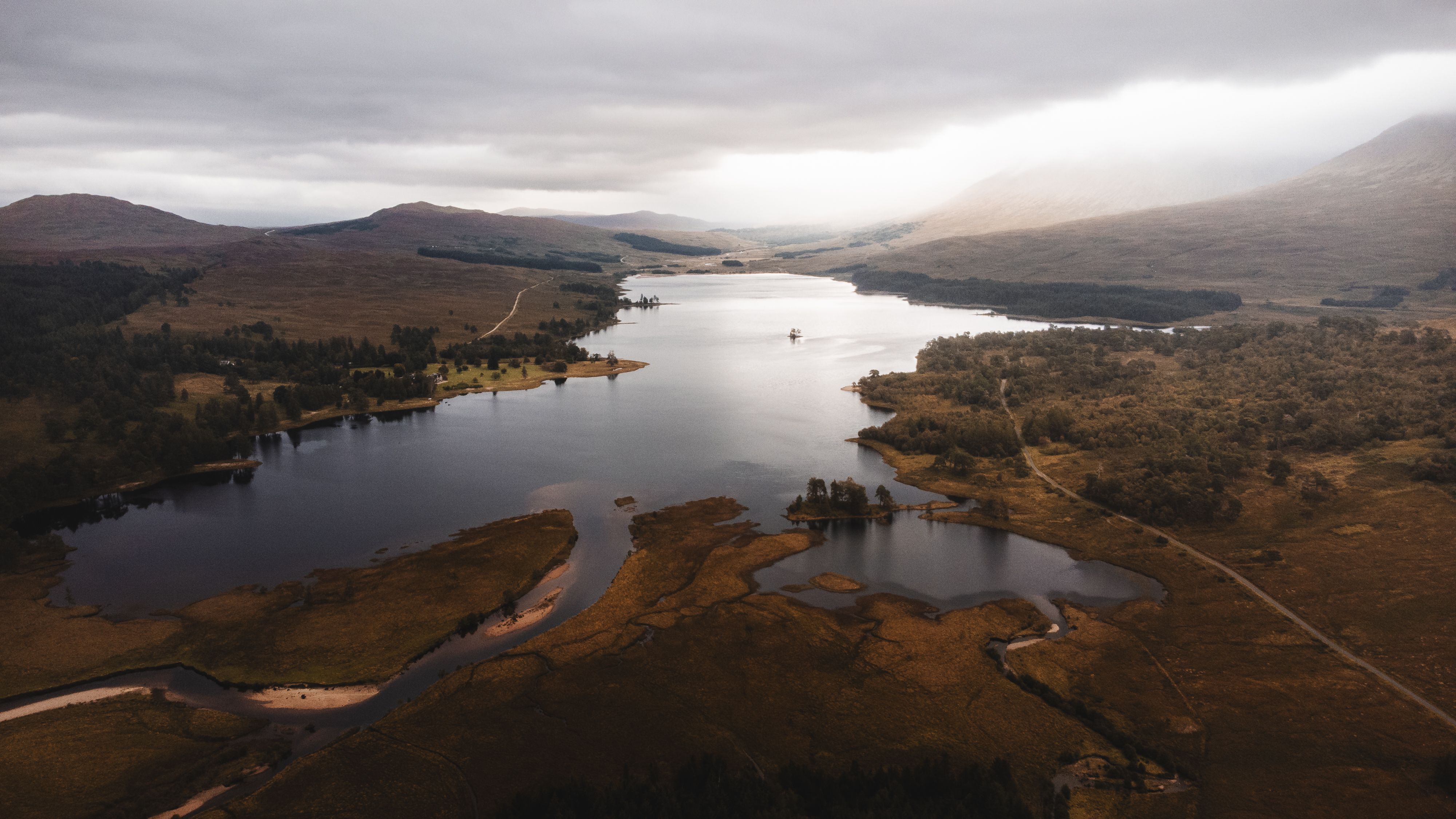 Dramatic aerial view of a loch surrounded by mountains in the Scottish Highlands